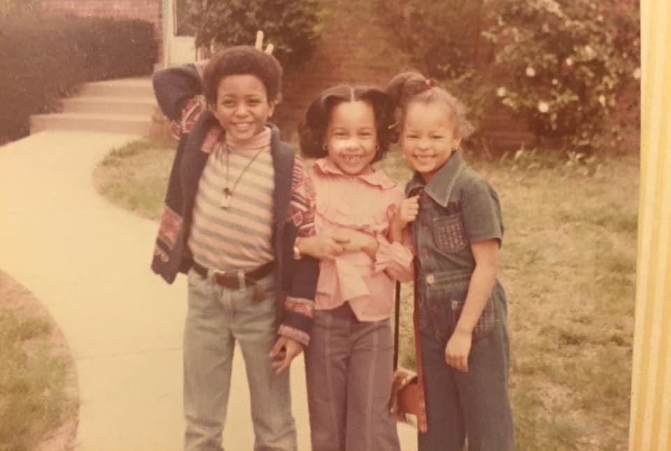Sonya as a young girl, arm in arm with two other children outdoors