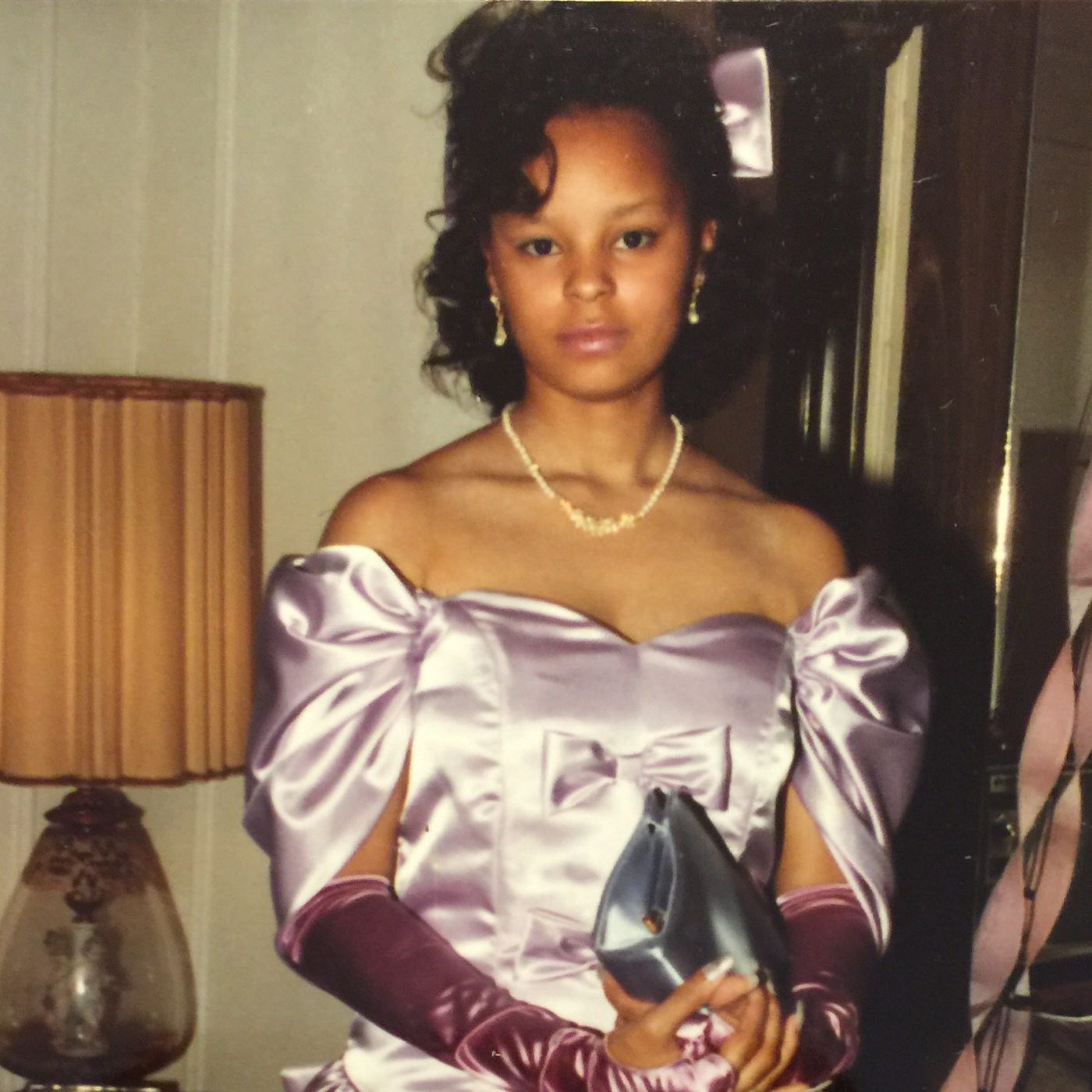 Sonya in a lavender satin gown with long gloves, holding a clutch
