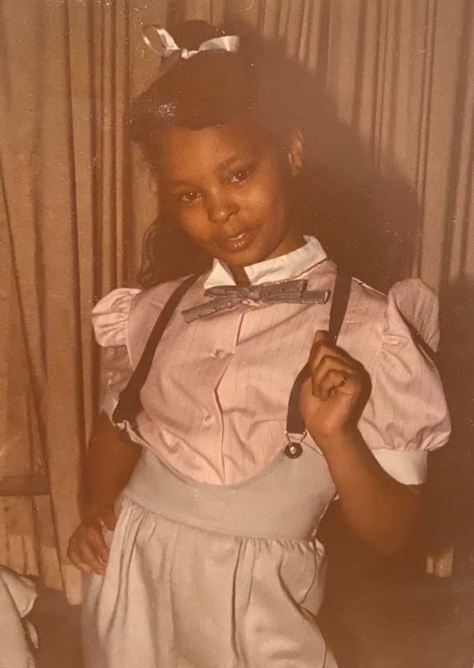 Sonya as a girl in a pink blouse, bow tie, and suspenders