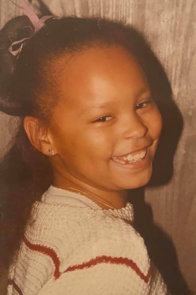 Sonya as a girl, laughing in a striped sweater