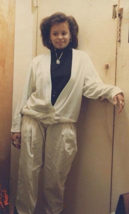 Sonya leaning against a door in a cream outfit
